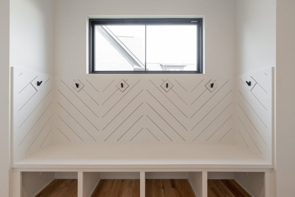 Contemporary Louisville foyer by luxury custom home builders featuring white chevron wall and sleek black hooks.