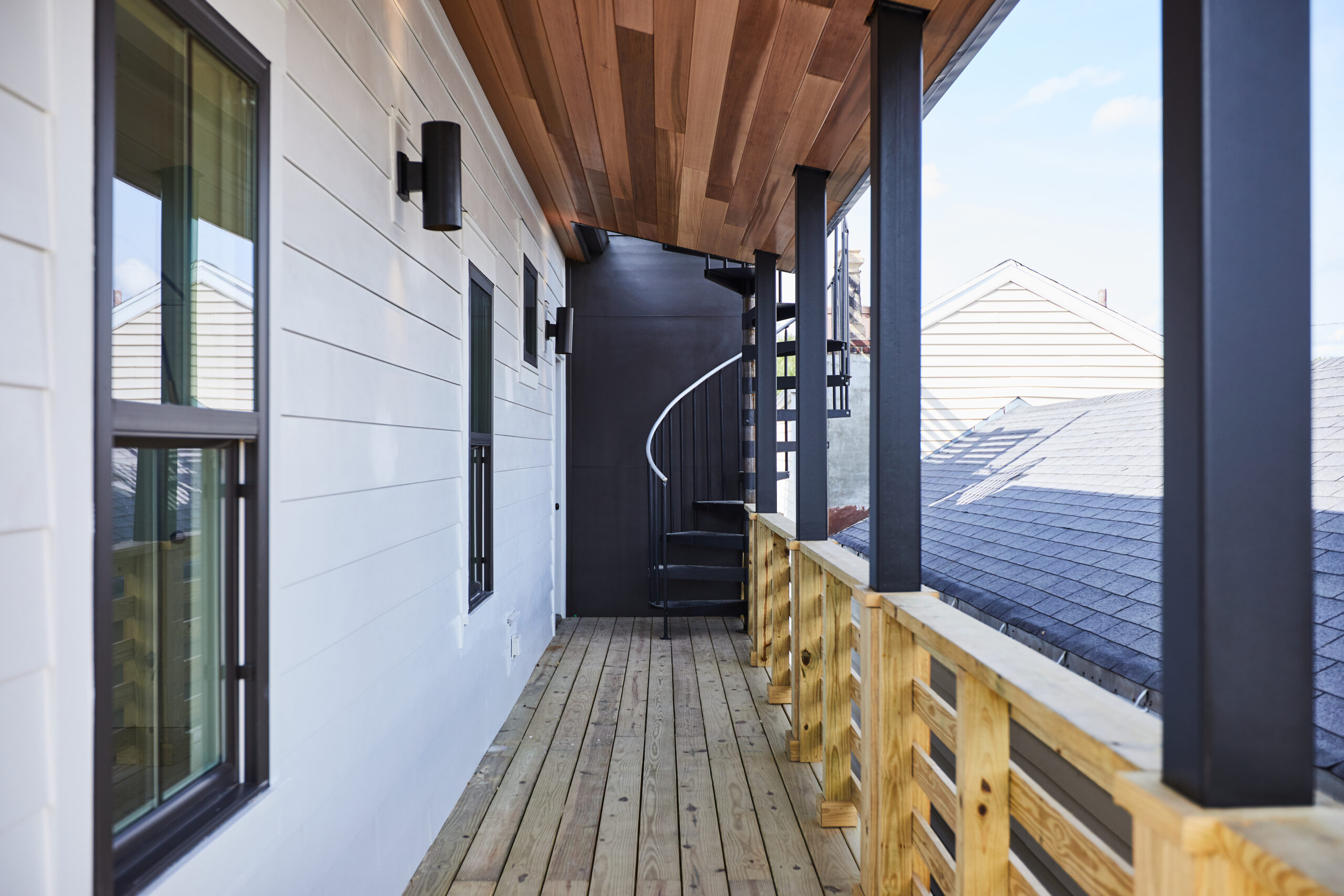 A modern wooden balcony with a spiral staircase, showing a stunning outdoor living space designed by a luxury custom home builder.
