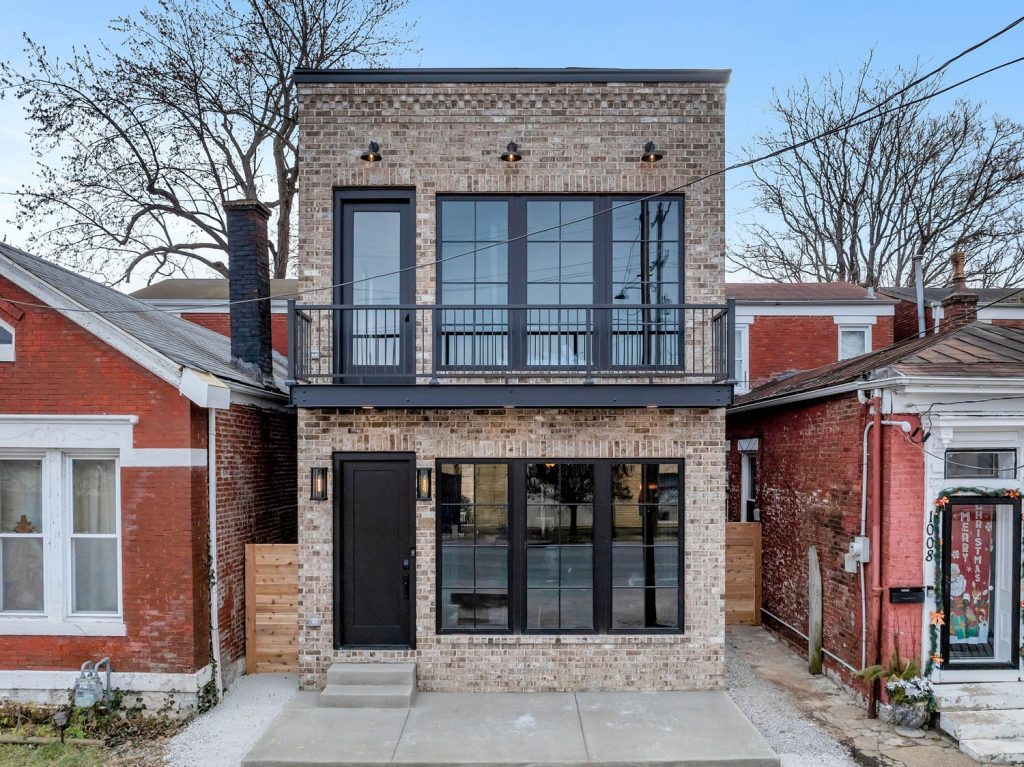 Louisville modern two-story brick home with black-framed windows, balcony, and sleek contemporary design.