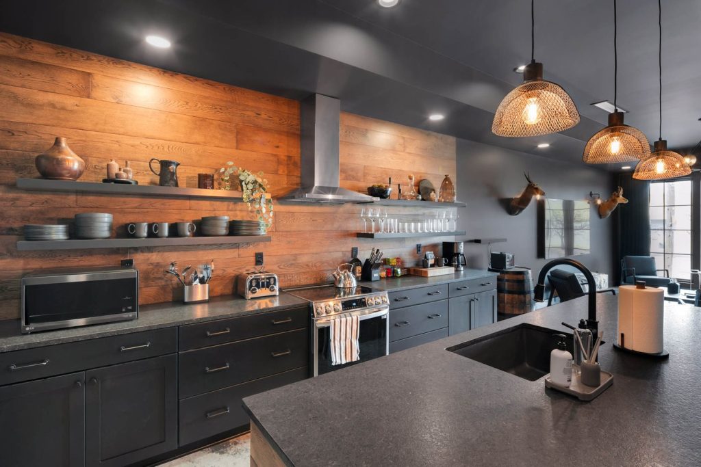 Louisville modern kitchen with dark cabinets, stone countertop, wooden backsplash, open shelves, and warm pendant light.