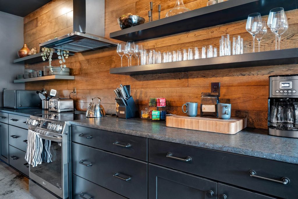 Louisville modern kitchen with dark cabinets, wood-paneled walls, open shelves, and cozy coffee and dining setup.