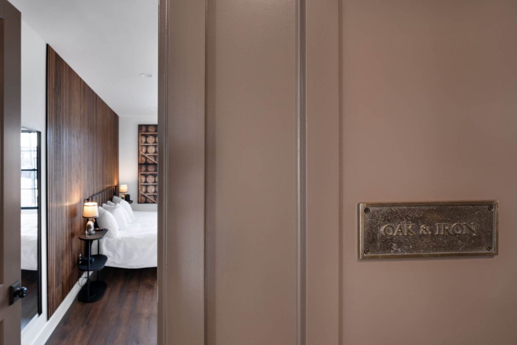 Louisville modern bedroom seen through open door, with wood accents, neatly made bed, warm lighting, and 
