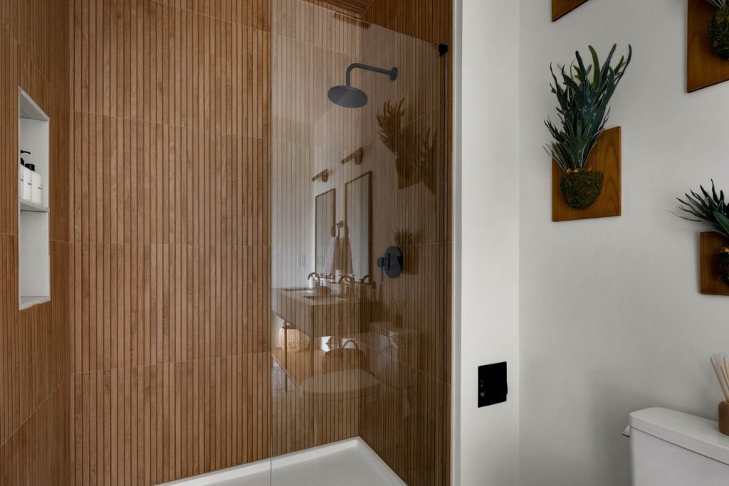 Louisville modern bathroom with wood-textured walls, glass shower, matte black fixtures, dual sinks, and custom home design details.
