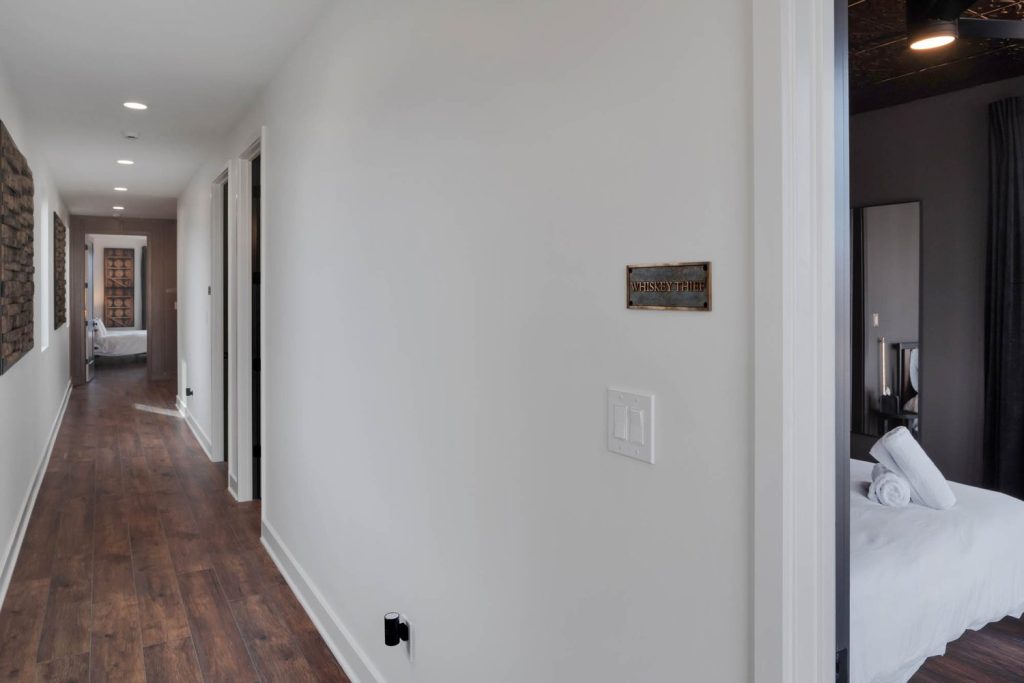 Minimalist hallway with white walls, dark wood floors, and subtle wall decor. Calm, tidy, and modern ambiance.