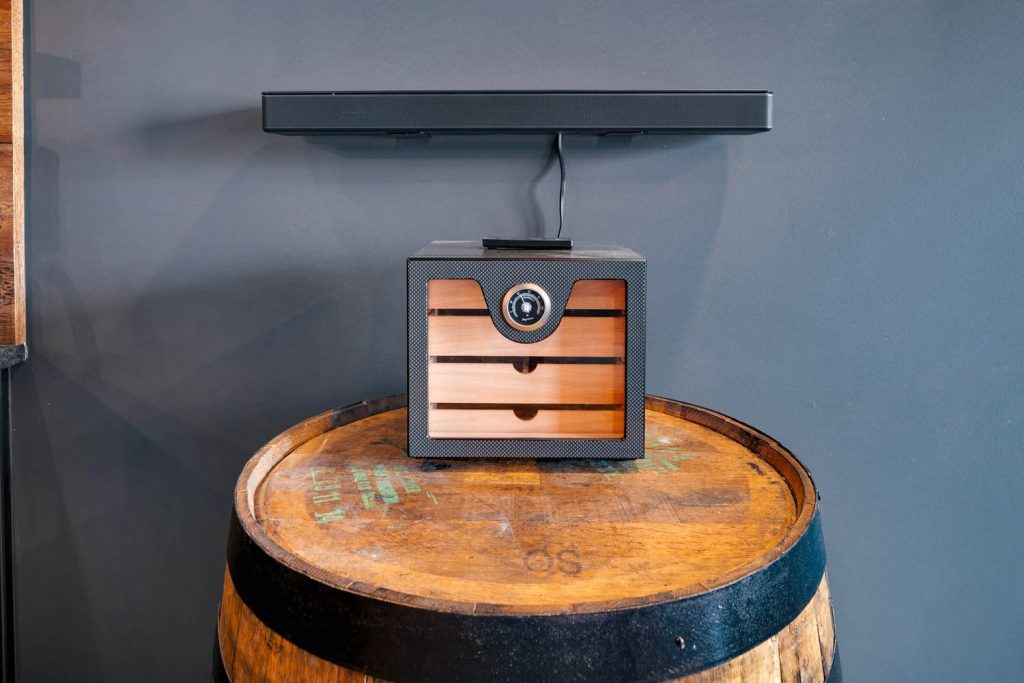 Louisville modern home with black humidor on rustic barrel, wooden drawers, and sleek soundbar, stylish vintage-modern mix