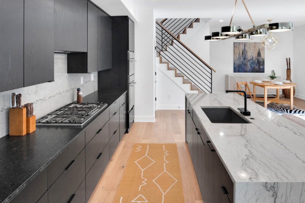 Modern kitchen with black cabinets, marble counters, and gas stove in a new construction home with clean, minimalist design.