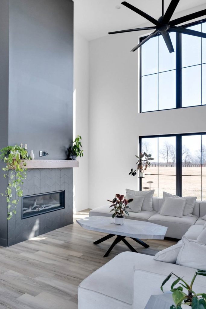 Spacious Louisville living room with gray fireplace, white sectional, and marble table by top modern home builders.