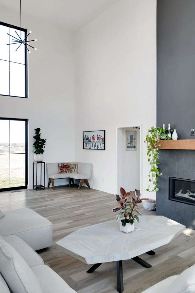 Louisville modern living room with gray fireplace, corner sofa, plants, and art, crafted by top custom home builders.
