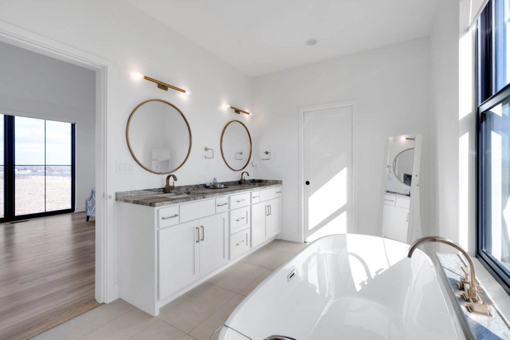 Louisville modern bathroom with dual sinks, round mirrors, freestanding tub, and serene custom home design style.