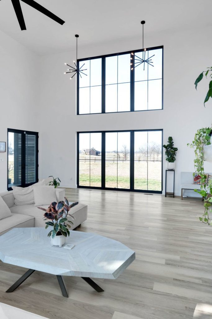 Louisville modern living room with high ceilings, white sofa, large windows, and greenery by top custom home builders.