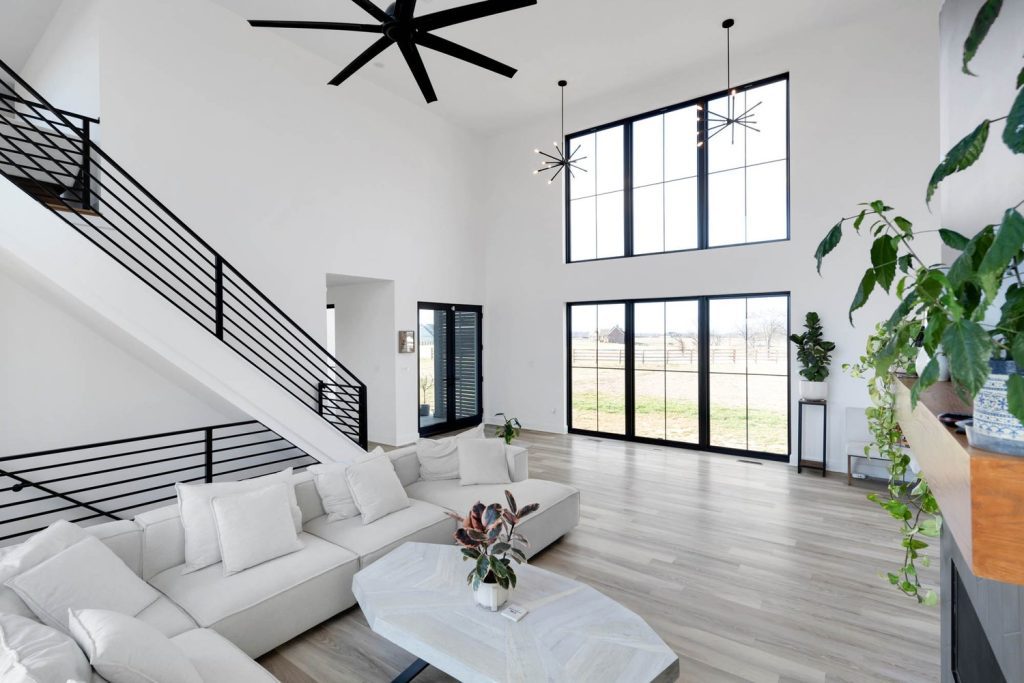 Louisville modern living room with light wood floors, white sofas, sleek staircase, and black ceiling fans.