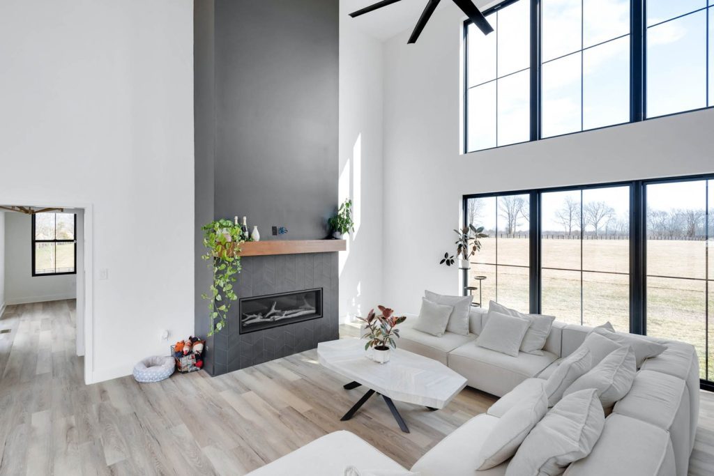 Open-concept Louisville living room with vaulted ceilings, stone fireplace, white sectional, and sunlit wood floors.