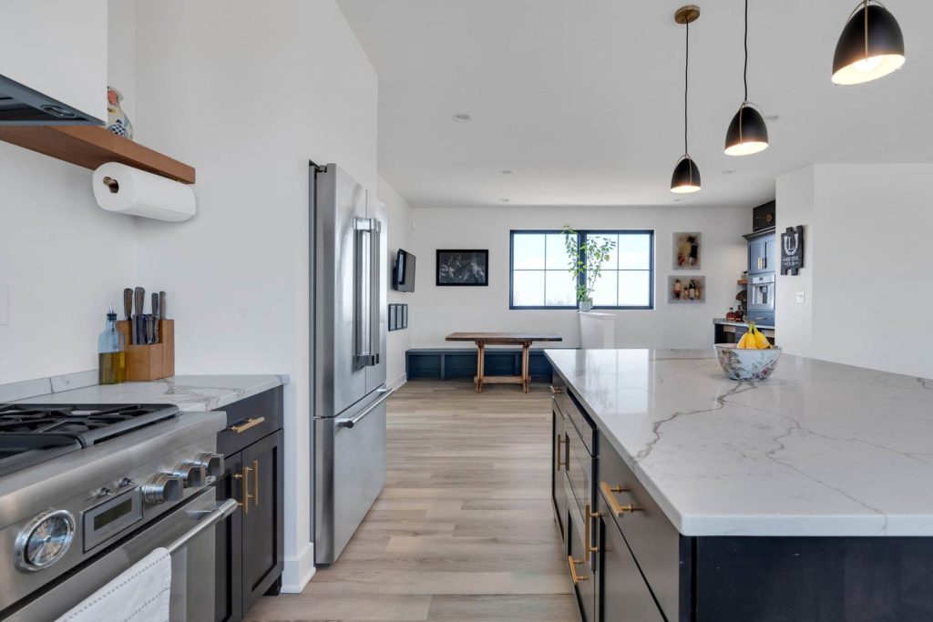 Louisville modern kitchen with dark cabinets, white countertops, sleek appliances, and bright dining area.