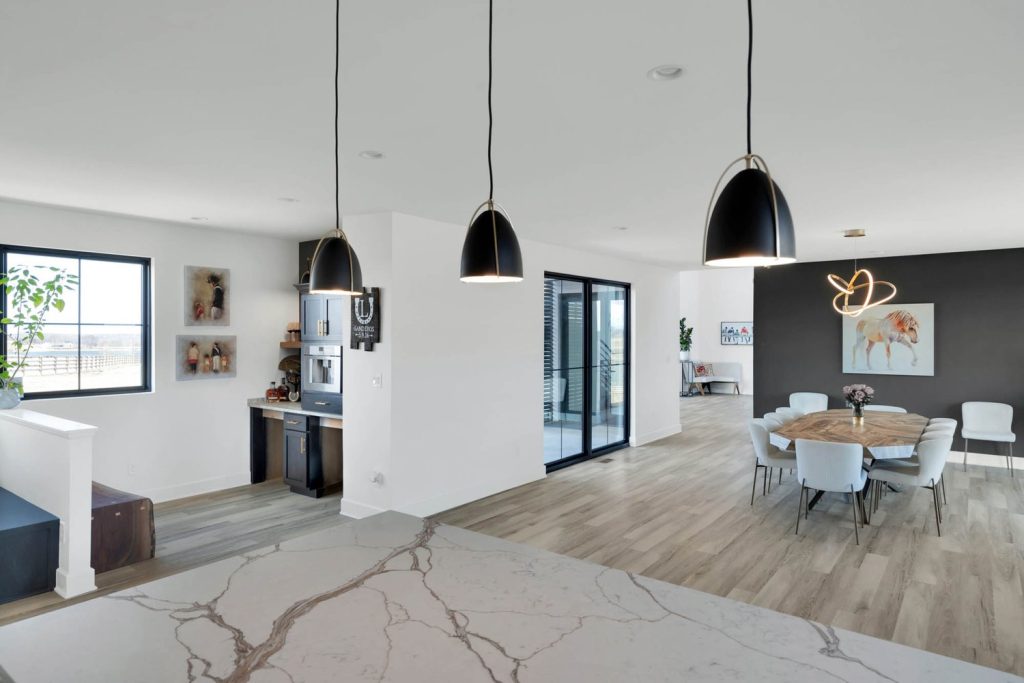 Louisville modern open kitchen with marble countertops, black pendant lights, wood floors, and large glass doors.