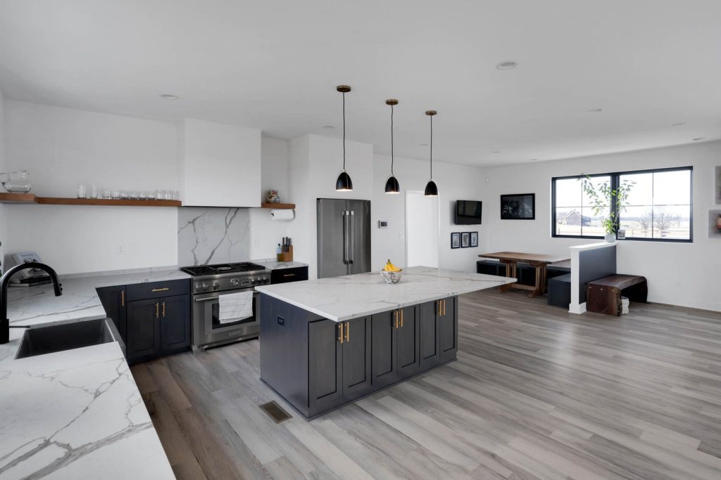 Louisville modern kitchen with gray cabinets, marble island, black pendant lights, and sleek stainless steel appliances.