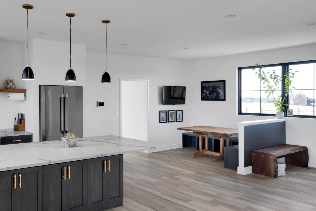 Louisville modern kitchen and dining with marble countertop, wooden table, benches, pendant lights, and light wood floors.