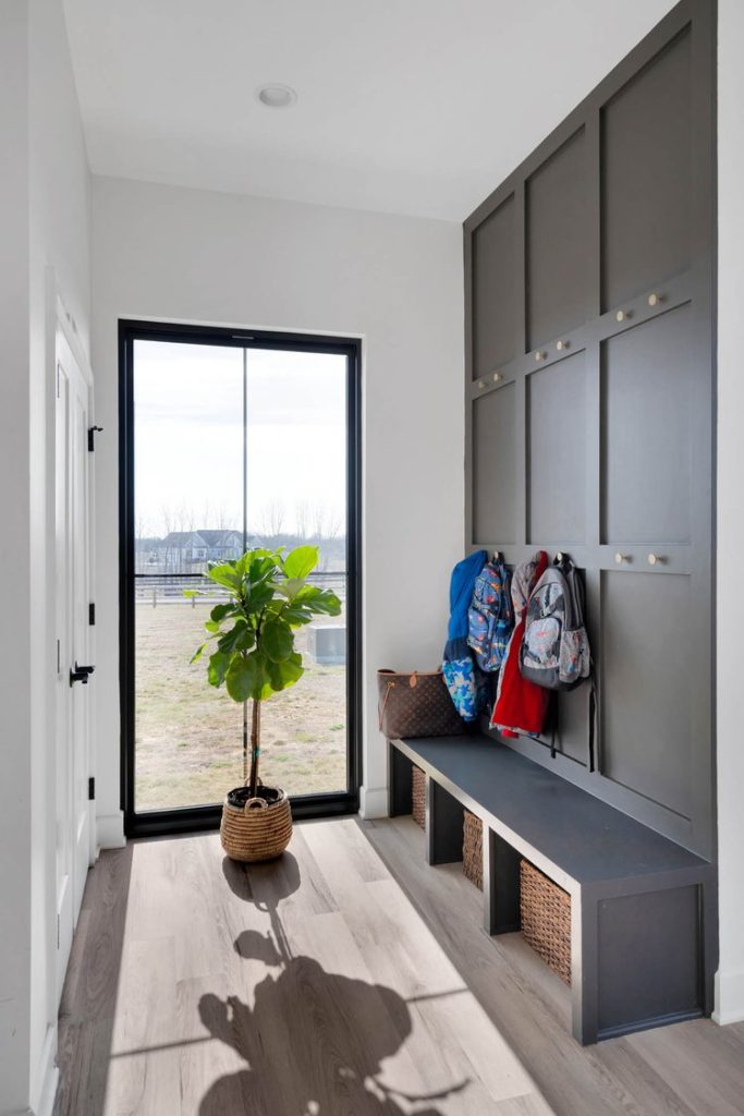 Louisville modern mudroom with scenic window, storage bench, baskets, and colorful backpacks on wall hooks.