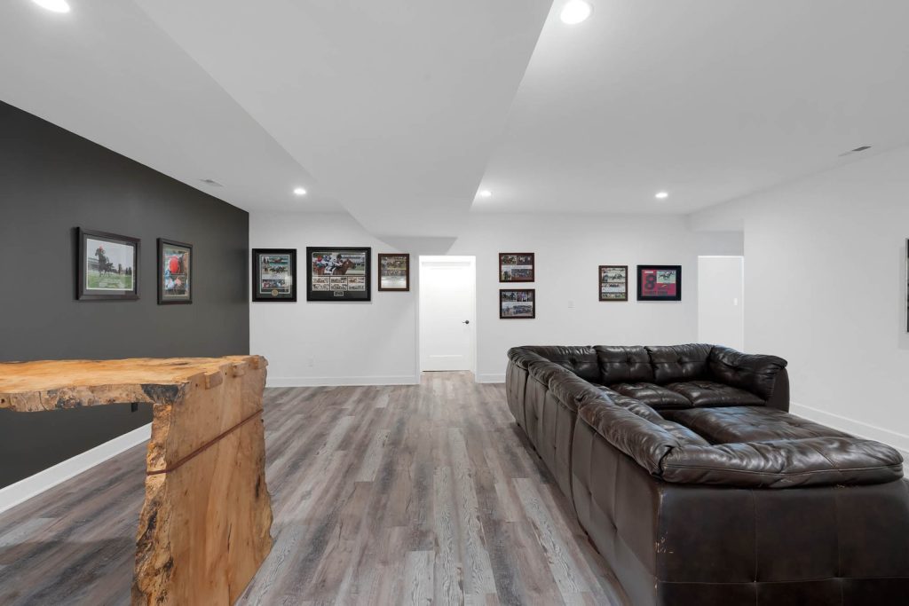 Louisville modern basement with L-shaped leather sofa, polished wood floors, framed walls, and cozy ambient lighting.