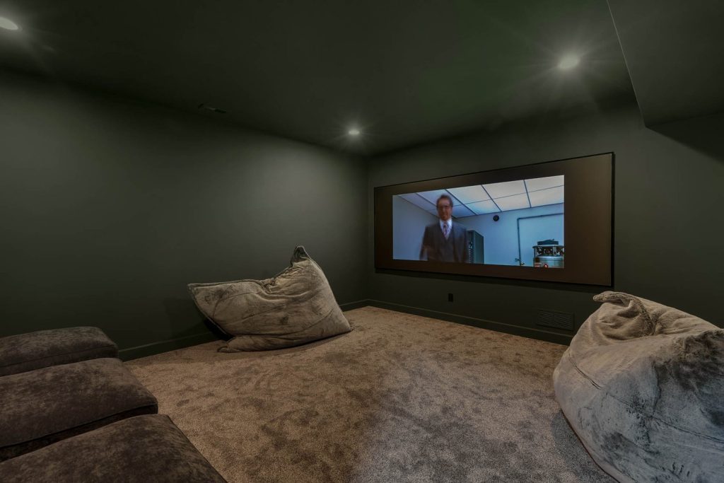Louisville modern home theater with dark walls, plush carpet, oversized bean bags, and large cinematic screen.