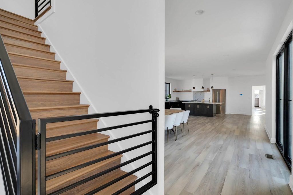 Louisville modern interior with wooden stairs, black railing, open kitchen, bar stools, and sleek minimalist design.