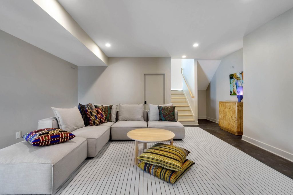 Modern living room with gray sectional, colorful pillows, and wood coffee table in a bright new construction home