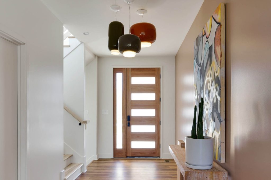 Cozy corner nook with blue cushioned seating, plaid backrests, accent pillows, and large windows with soft natural light