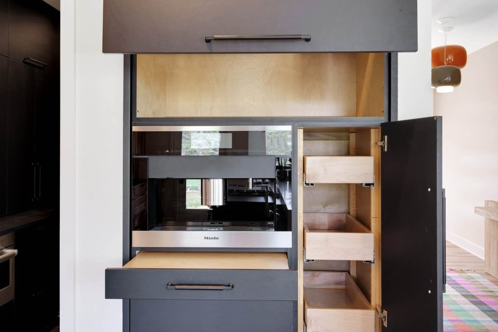 Modern kitchen storage with black and wood design, open shelves, wall oven, and pull-out drawers for an organized look