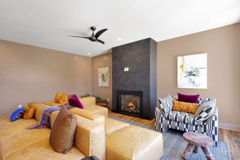 Sunlit modern room with U-shaped wooden bench, blue cushions, plaid backrests, and decorative pillows for a cozy feel