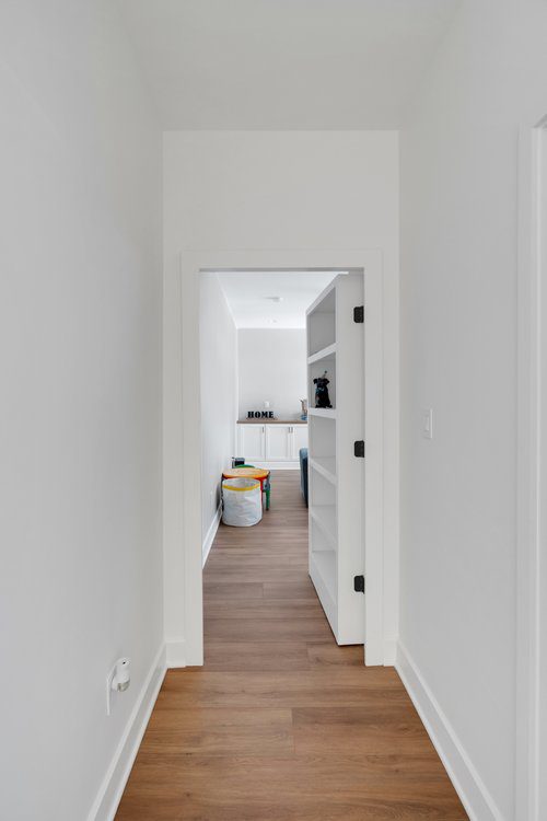 Minimalist hallway in Louisville home with light wood floors, bright open room, and playful decor by top custom home builders.