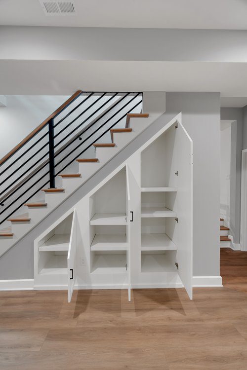Modern under-stair storage in Louisville home with white cabinets and minimalist design by top custom home builders.