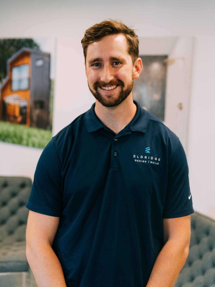 Michael Paquin, Louisville project manager, smiling indoors with modern home photos behind him.