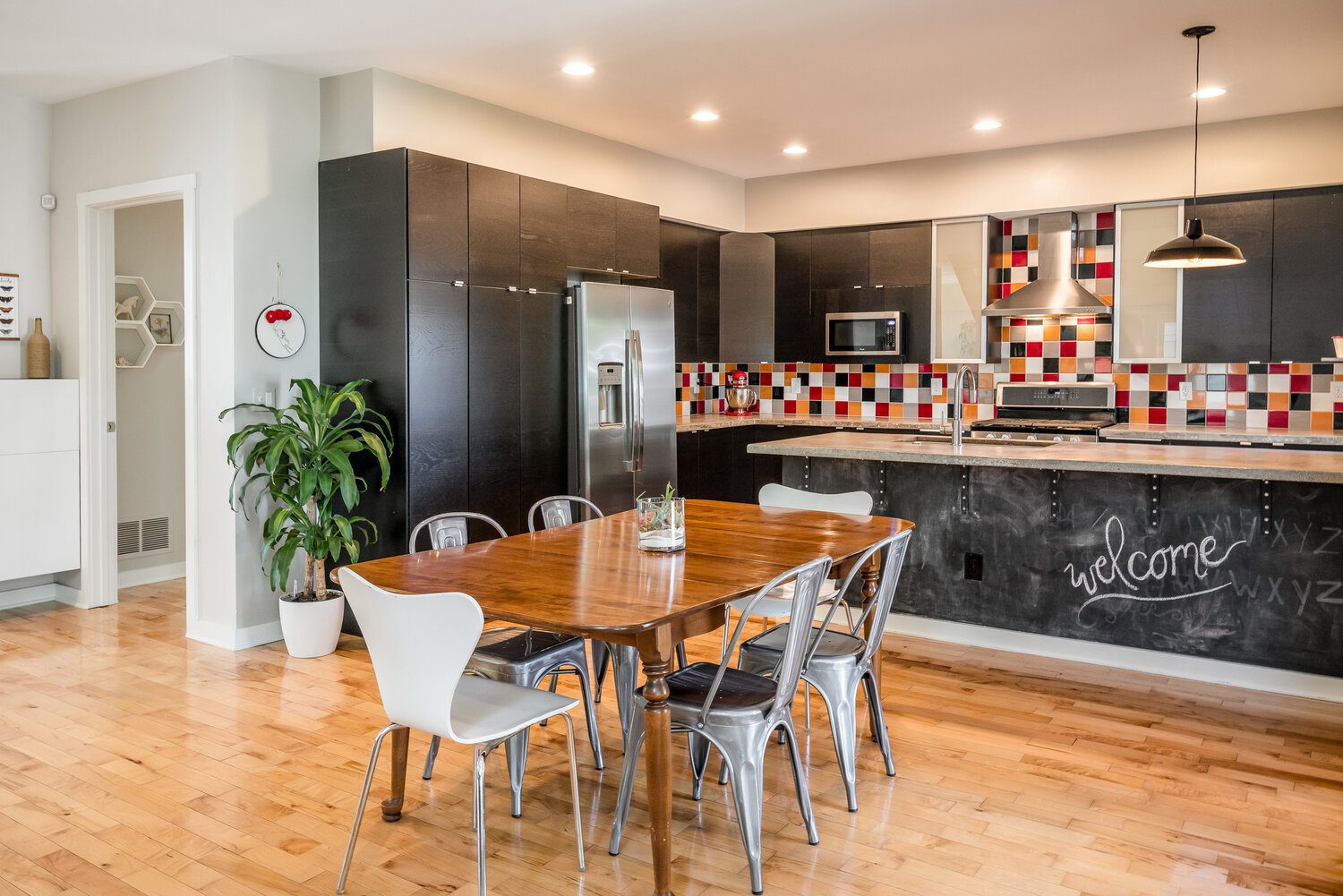 A modern kitchen with dark cabinets, a wooden dining table, and a colorful backsplash, showing the personalized design of a custom home.