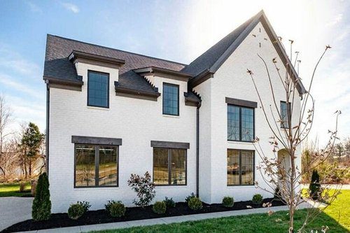 Stylish white brick custom home in Louisville with black-trimmed windows, built by a leading custom home builder.