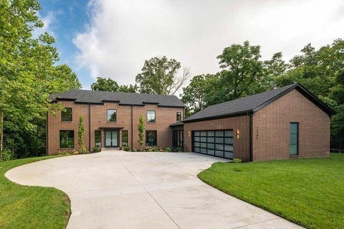 Modern brick custom home in Louisville with large windows and a spacious driveway by top local home builders.