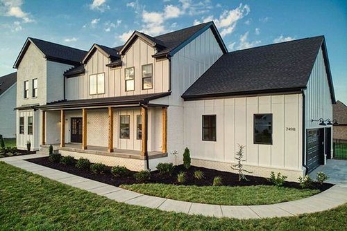 Elegant two-story Louisville home with cream siding and wood-beam porch, crafted by a trusted custom home builder.