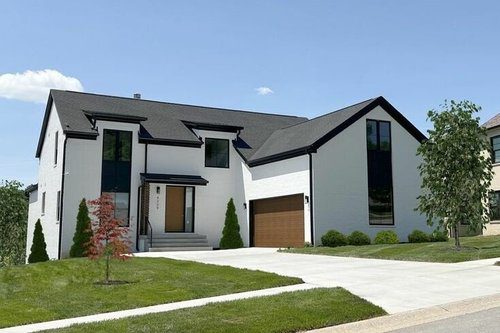 Stylish modern home in Louisville with white exterior, dark trim, and wood garage door by a leading custom home builder.