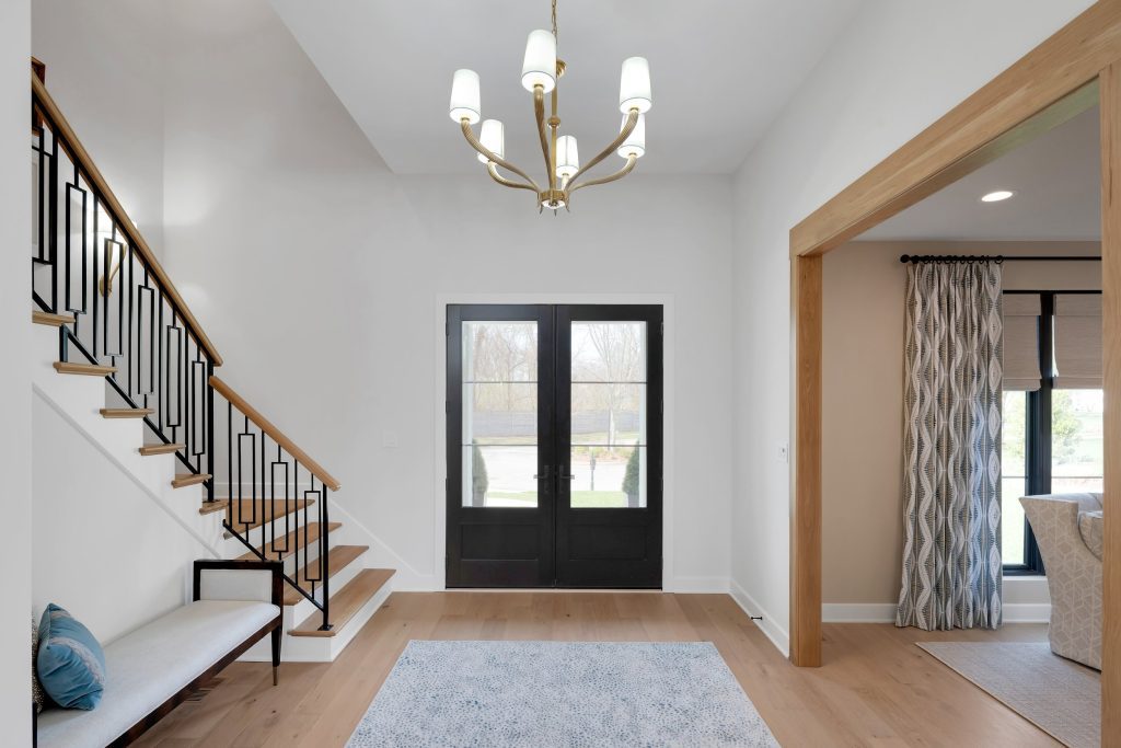 Louisville modern entryway with sleek staircase, black double doors, and statement chandelier by top custom home builders.