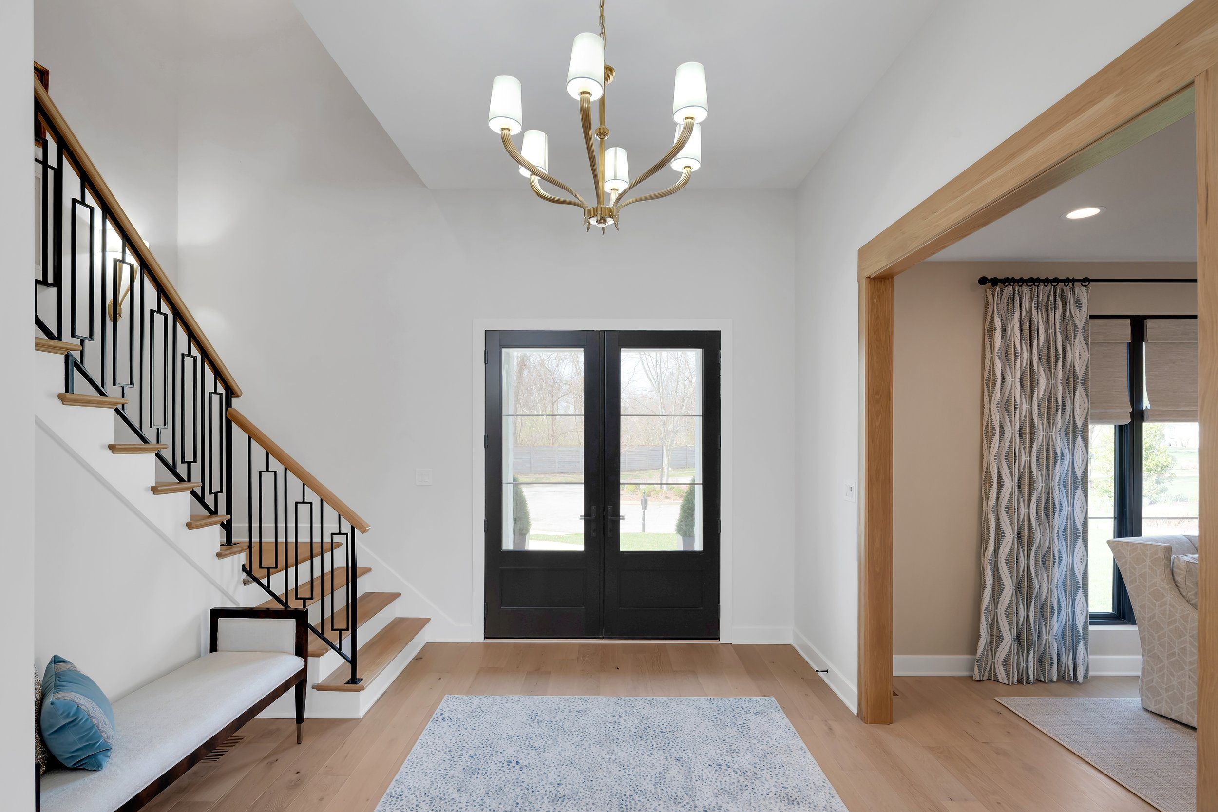 Louisville modern entryway with sleek staircase, black double doors, and statement chandelier by top custom home builders.