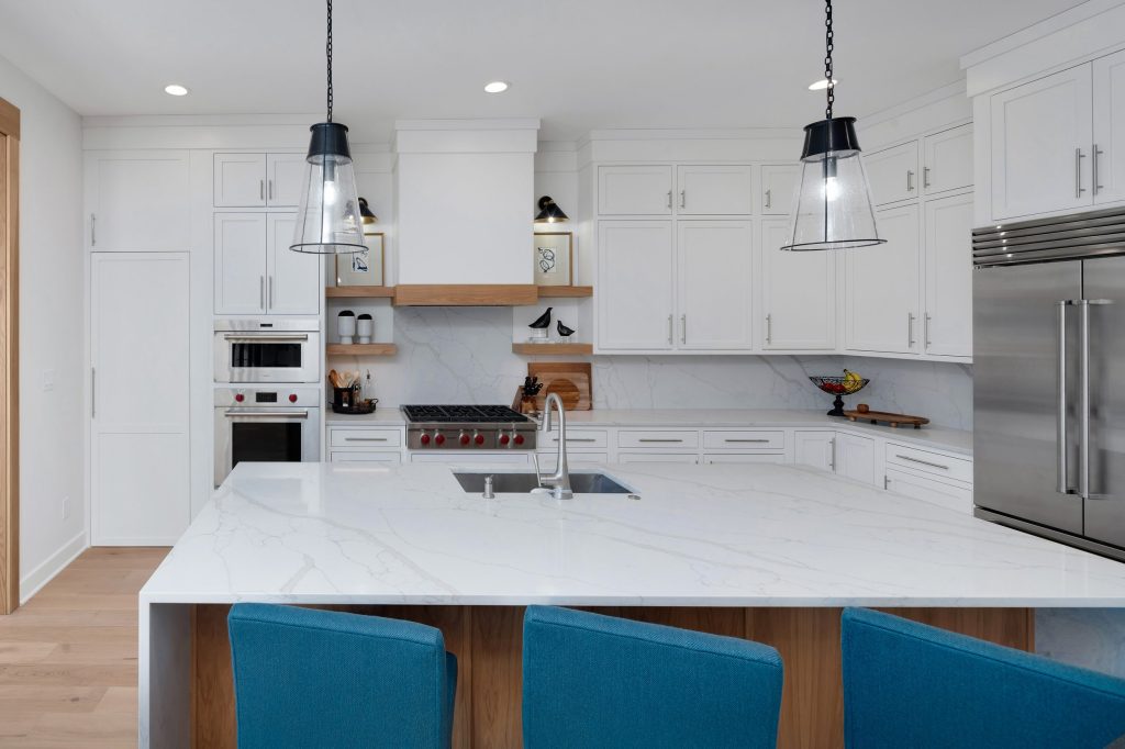 Louisville modern kitchen with white cabinets, marble countertops, and blue bar stools by top custom home builders.