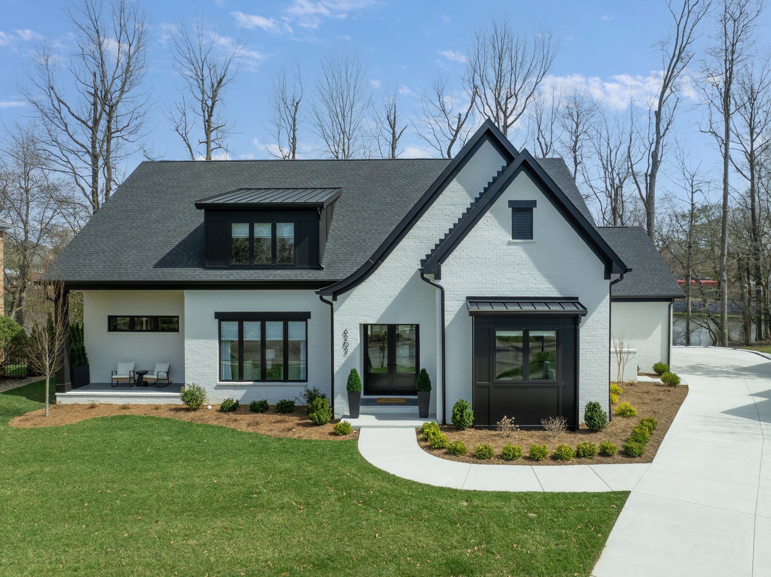 Louisville modern white brick home with black roof, large windows, and curved driveway by top custom home builders.