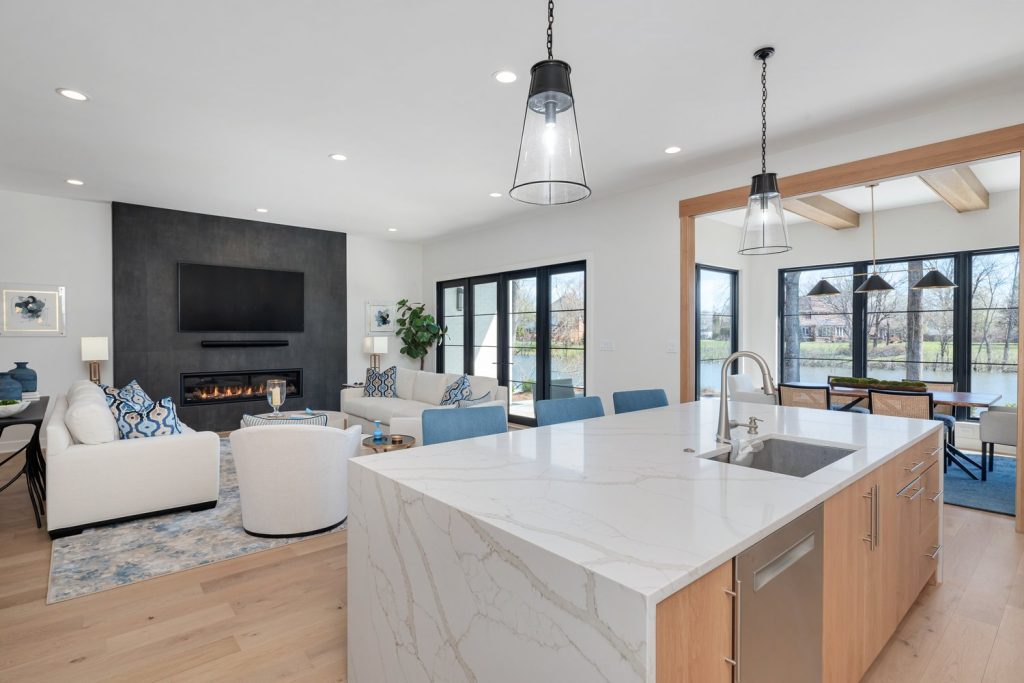 Louisville modern open-concept living room and kitchen with marble island and sleek fireplace by top custom home builders.