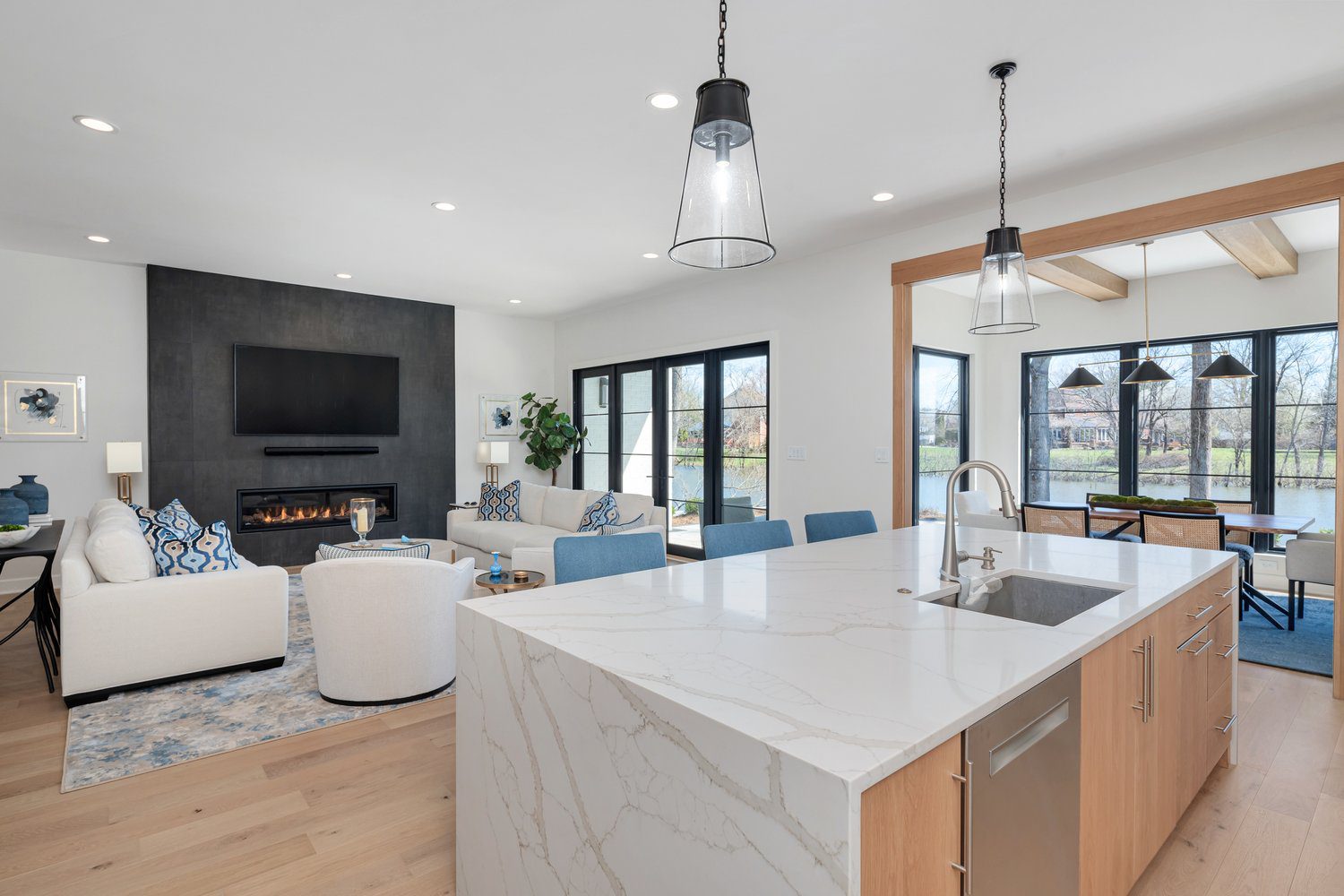 Louisville modern open-concept living room and kitchen with marble island and sleek fireplace by top custom home builders.