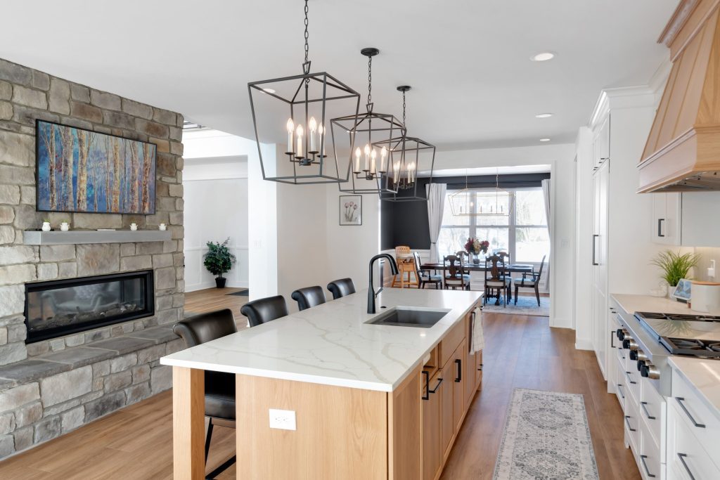 Louisville modern kitchen with marble island, black chairs, geometric chandeliers, and cozy dining by top custom home builders.