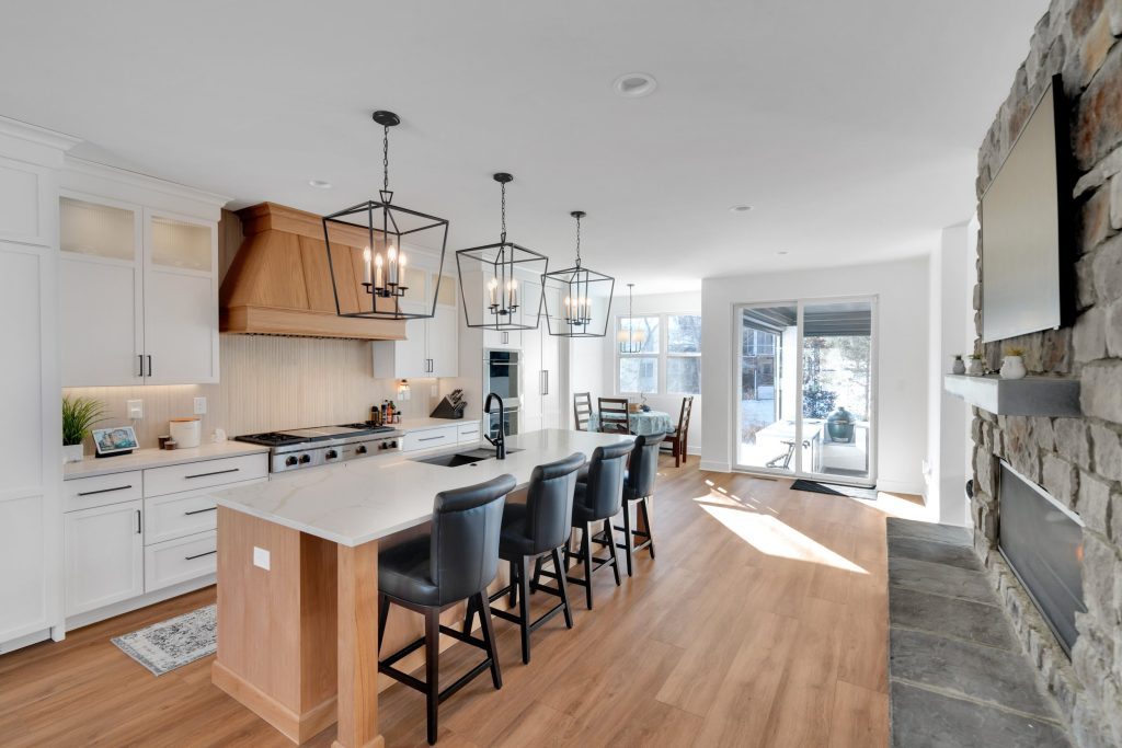 Louisville modern kitchen with large island, leather stools, pendant lights, and bright windows by top custom home builders.