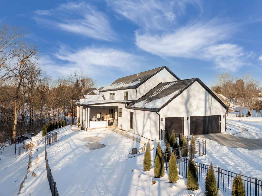 Modern Louisville home with snowy yard, large windows, and porch by top custom home builders Eldridge Company.