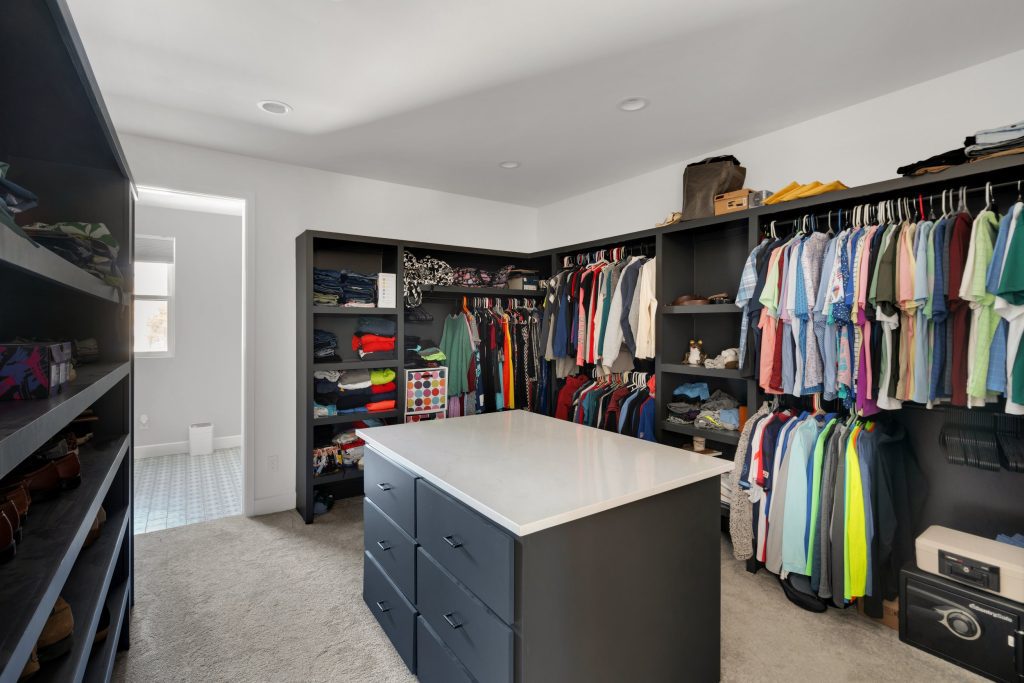 Bright and organized walk-in closet in luxury custom home with dark shelving and center island.