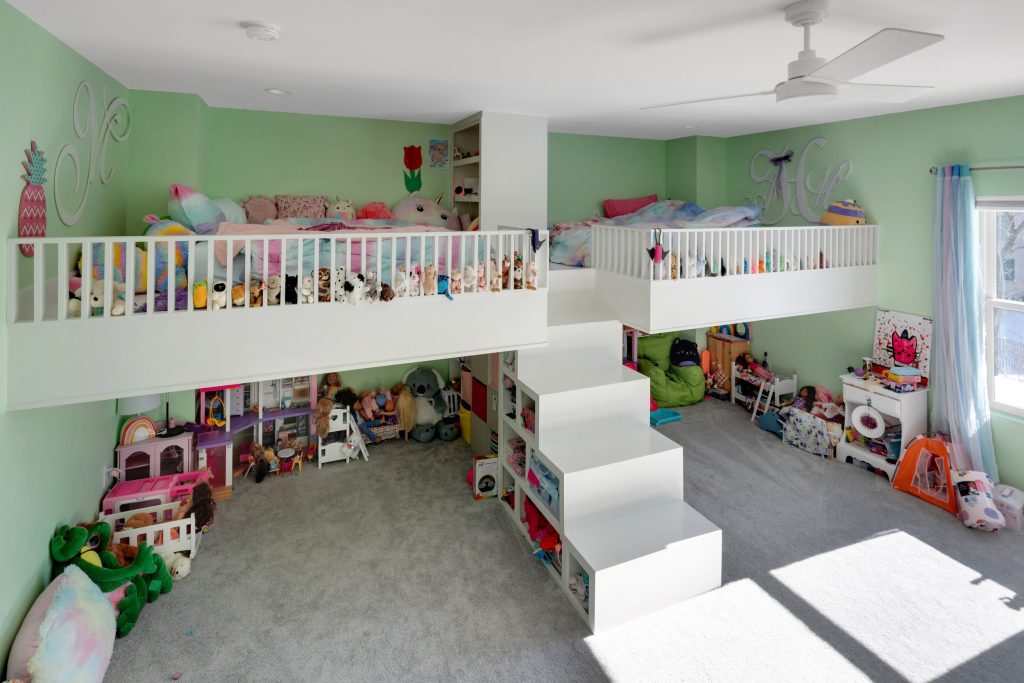 Two-story playroom in Louisville custom home with lofted spaces, central staircase, and organized toys.