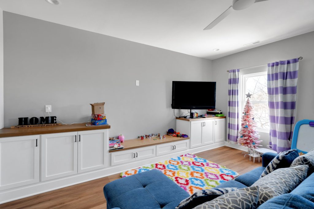 Louisville modern living room with colorful toys, rainbow rug, white cabinets, and festive pink Christmas tree.