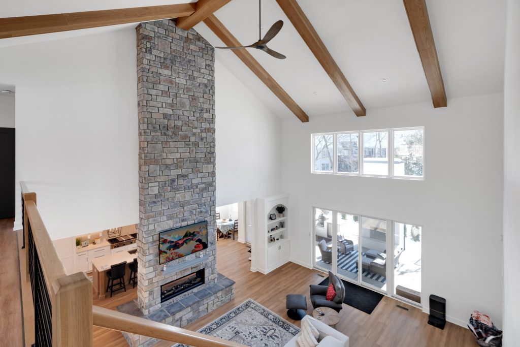 Louisville modern farmhouse living room with stone fireplace, exposed beams, large windows, and warm, inviting style.