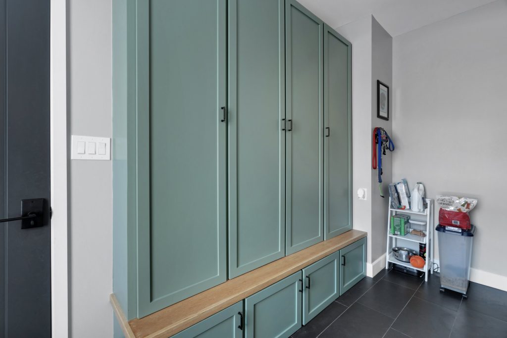 Louisville modern farmhouse built-in green cabinets with wooden bench, organized shelves, and functional storage space.
